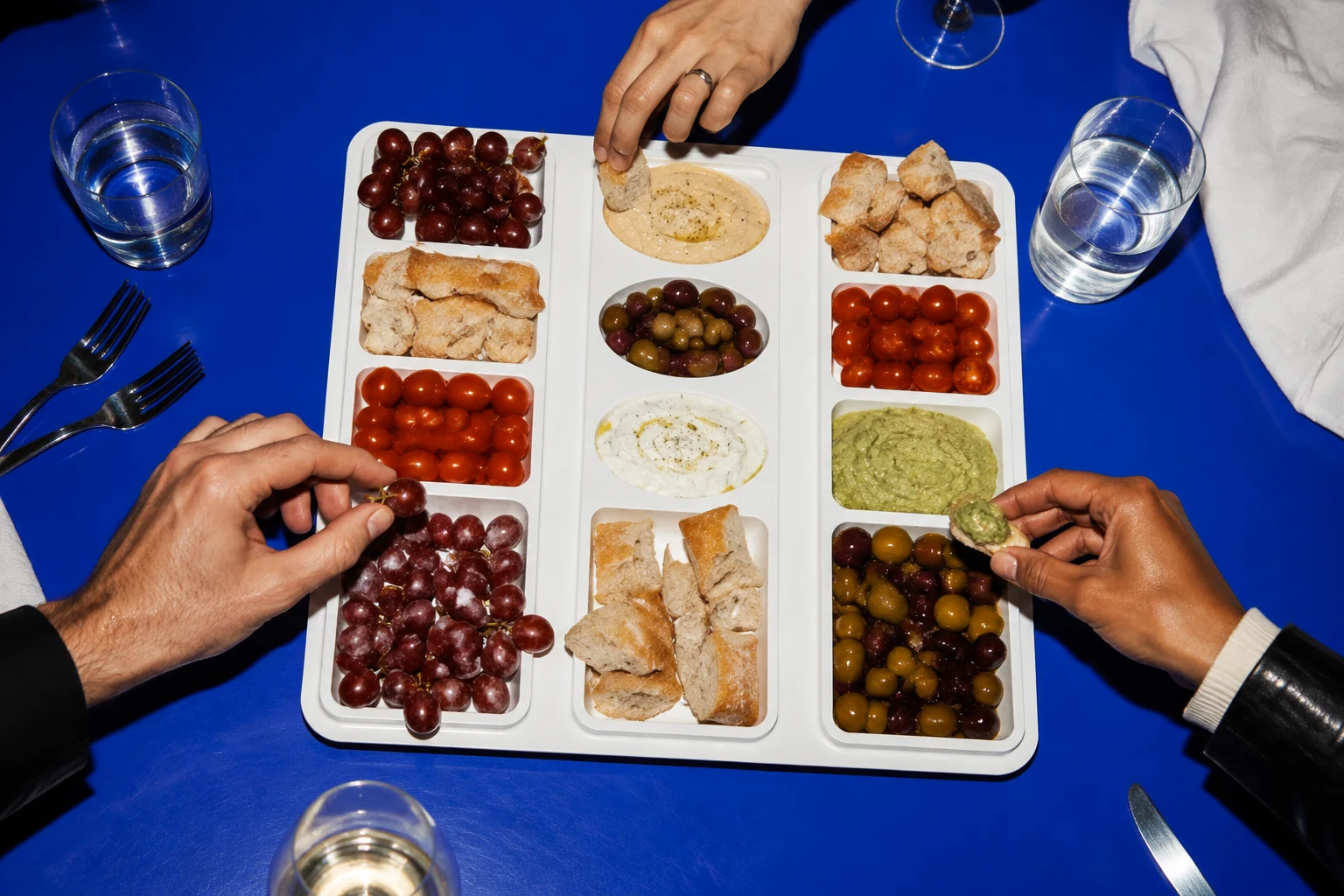 Friends reaching for a shared spread in the Throwaway Buffet tray